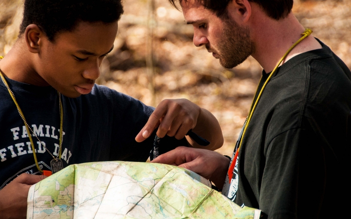 Two people people examine a map that one of them holds.